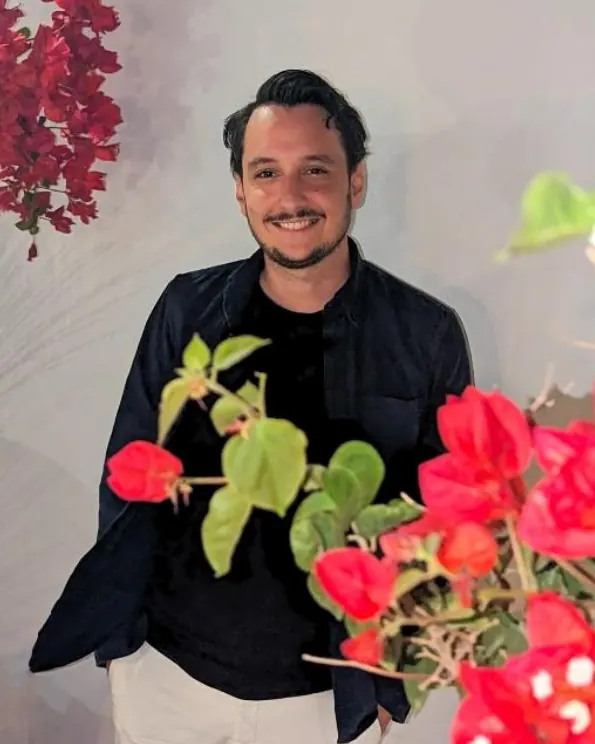 Charles Antonas, French teacher and speaking coach, smiling among bougainvillea